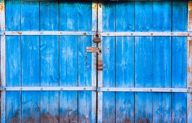 Viejas puertas grandes de madera pintadas en azul y cerradas en el candado