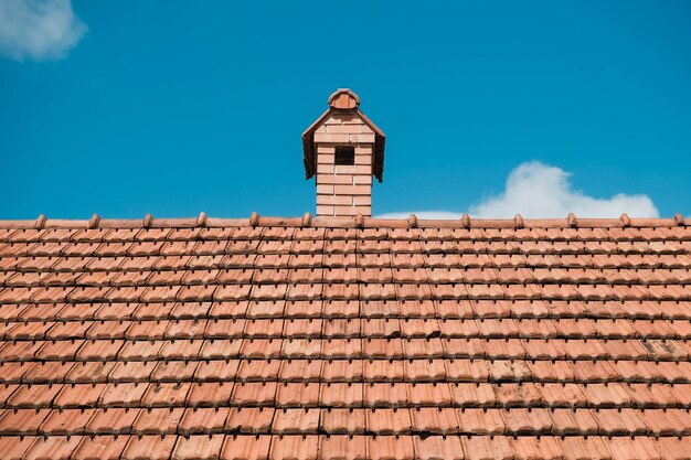 Viejas tejas en el techo de una casa con chimenea en el fondo del cielo. Lugar para texto o publicidad.