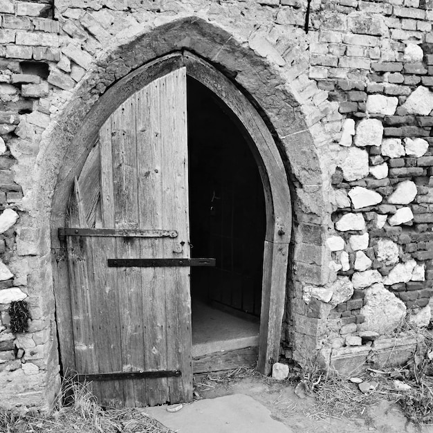 Viejo abre la puerta de la iglesia con una pared de ladrillo