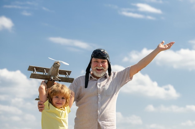 Viejo abuelo y nieto de niño pequeño con avión de juguete sobre fondo de cielo azul nubes hombres gene...