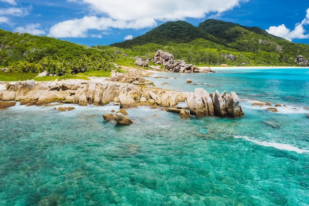 Viejo arrecife de coral en la playa de arena blanca en la playa aislada de Grand Anse La Digue Seychelles Antena