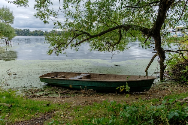 Viejo barco de madera en el río bajo las ramas de un árbol