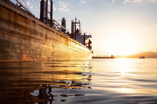 El viejo barco oxidado está estacionado en el puerto durante una vibrante puesta de sol