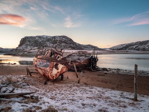 Un viejo barco pesquero oxidado abandonado por una tormenta en la orilla. Cementerio de barcos, antiguo pueblo de pescadores en la orilla del mar de Barents, la península de Kola, Teriberka, Rusia.