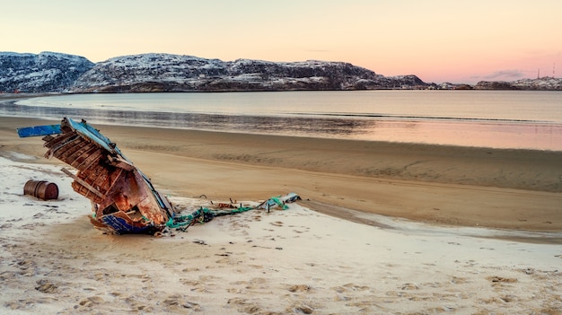 Un viejo barco pesquero oxidado abandonado por una tormenta en la orilla. Cementerio de barcos, antiguo pueblo de pescadores en la orilla del mar de Barents, la península de Kola, Teriberka, Rusia.