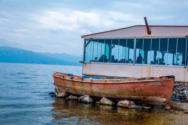 Un viejo bote de remos decrépito está varado en el borde del restaurante del lago. Restaurante con vista al lago. Podrido