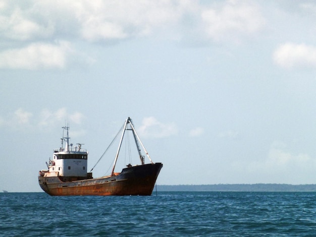 Un viejo buque de carga está anclado en el mar contra un cielo con nubes y olas tranquilas tipo marino de trans