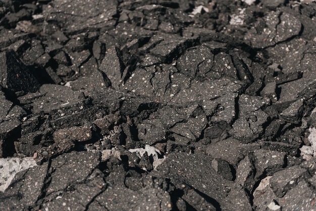 El viejo camino de asfalto agrietado está dañado en el suelo para ser reciclado. Concepto para reducir la reutilización y el reciclaje. Primer plano de asfalto agrietado viejo. Seleccione el foco. Fondo de textura gris