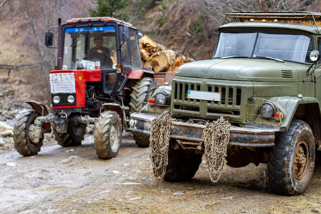 Un viejo camión militar en el pantano de color verde con cadenas de metal y un tractor forestal