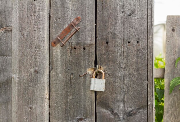 Un viejo candado oxidado cuelga de una vieja puerta de madera