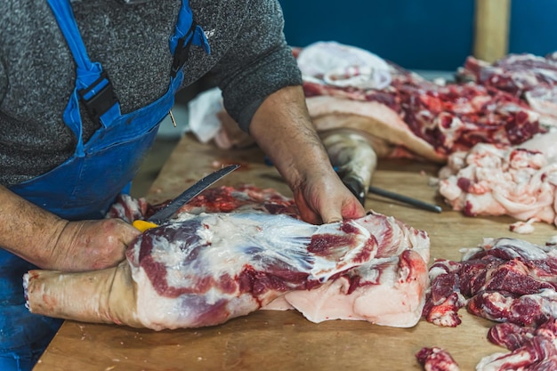 Viejo carnicero trabajando en la tienda cortando y preparando la carne para la venta