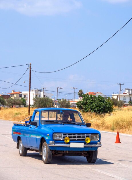 Foto viejo coche azul con faros redondos en la calle en grecia