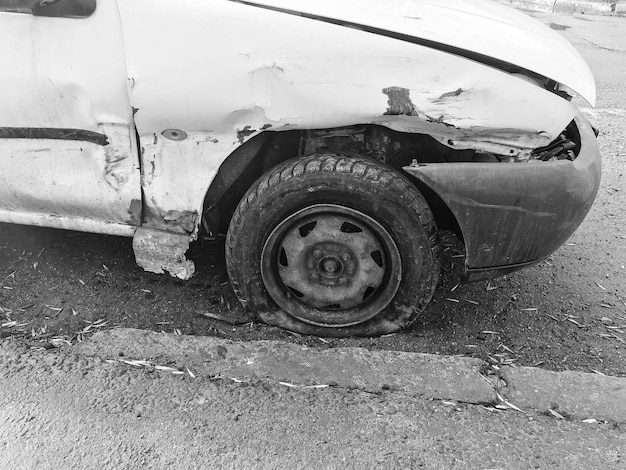 Viejo coche blanco oxidado roto de la carcasa con ruedas perforadas bajadas con arañazos