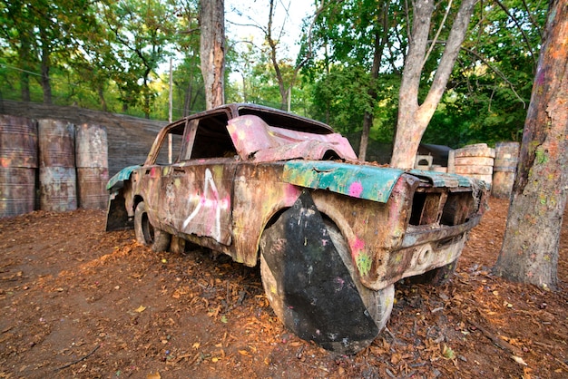 Un viejo coche oxidado y abandonado en una base de paintball