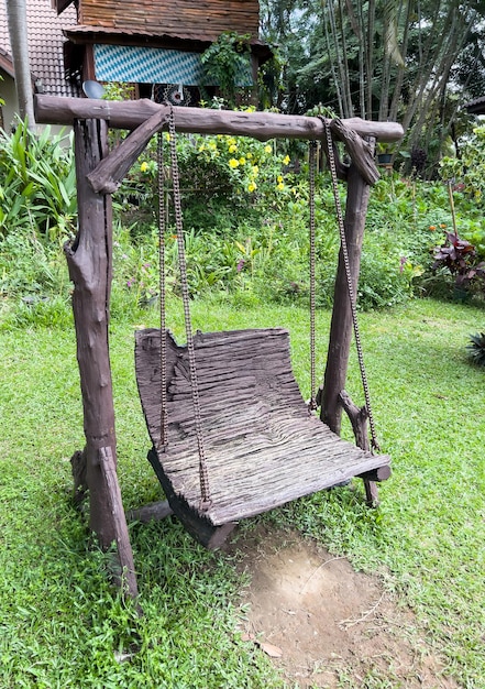 El viejo columpio de madera con cadena de metal para jugar en el jardín de la casa de campo, vista frontal con espacio de copia.