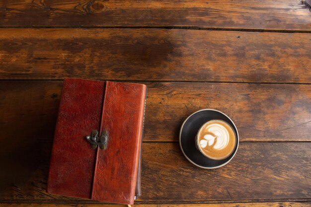 Viejo cuaderno y un café en una mesa de madera