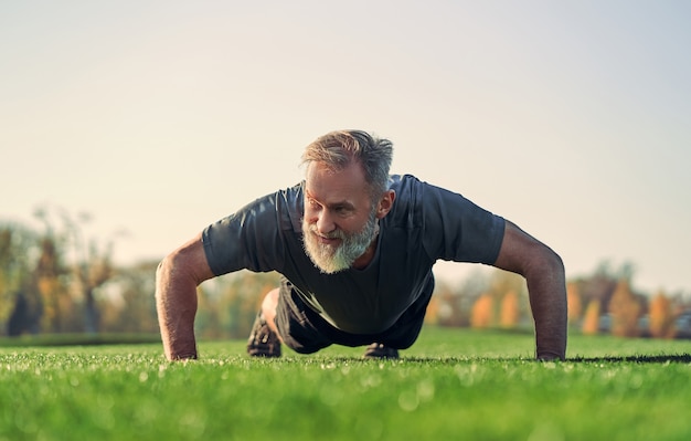 El viejo deportista empujando hacia arriba sobre la hierba