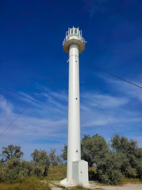 Viejo faro blanco en la isla contra un cielo azul brillante con nubes