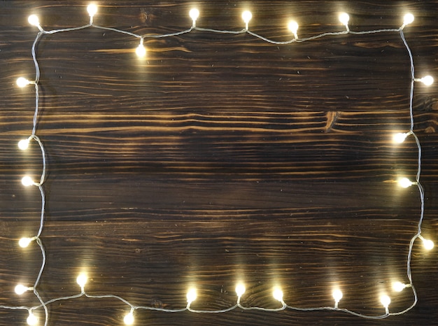 Viejo fondo de madera marrón con cálidas luces navideñas desde arriba