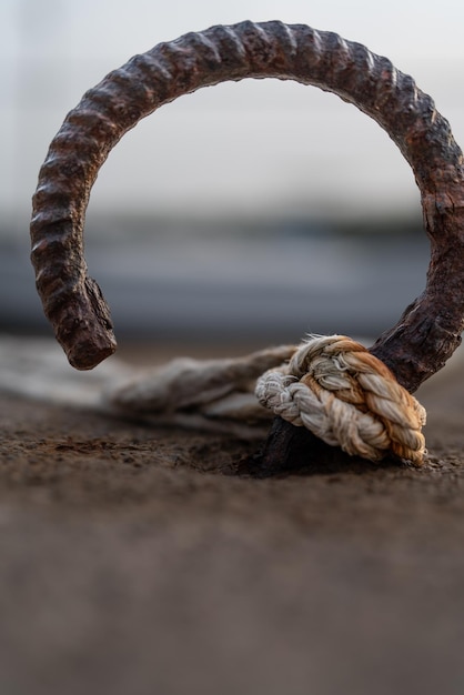 Viejo gancho oxidado en el muelle con una cuerda atada