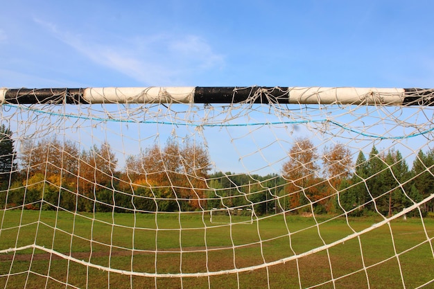 Viejo gol de fútbol contra el fondo del campo de fútbol y el bosque de otoño