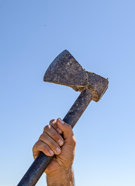 Foto viejo hacha de hierro en la mano contra el cielo