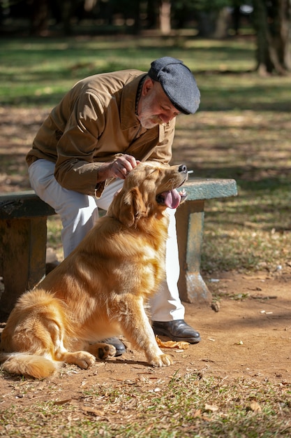 Foto viejo hombre acariciando un perro golden retriever