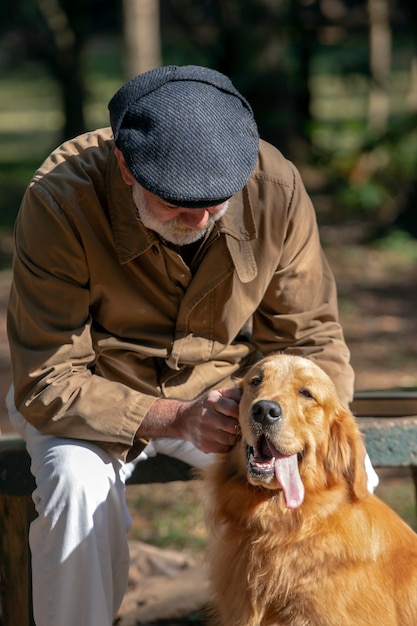 Foto viejo hombre acariciando un perro golden retriever