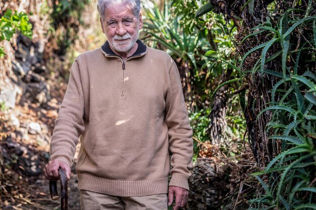 Viejo hombre barbudo senior en excursión al aire libre con ayuda de bastón