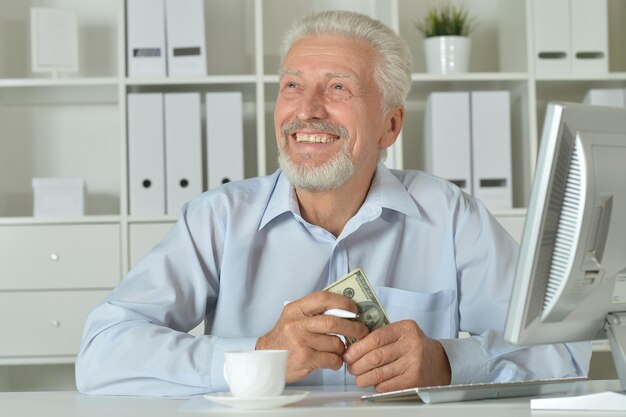 Viejo hombre de negocios con una computadora portátil trabajando en la oficina