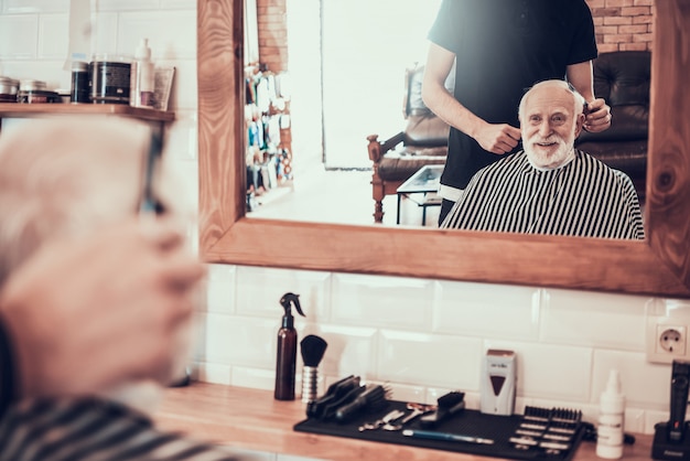 El viejo hombre vino al peluquero joven para el corte de pelo del estilo