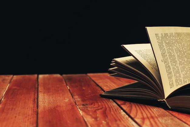 Un viejo libro abierto en una mesa de madera roja un hermoso fondo oscuro