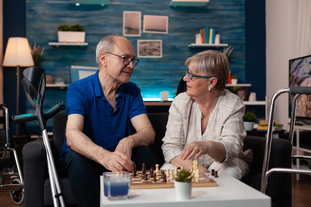 Foto viejo marido y mujer jubilados disfrutando de un juego de ajedrez