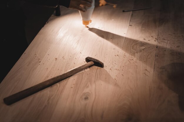 Un viejo martillo con un mango largo Pequeñas herramientas de trabajo de un carpintero en una mesa polvorienta
