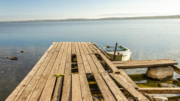 Un viejo muelle de madera con un bote en el lago.