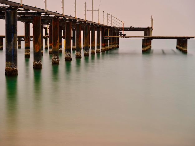 Viejo muelle en la playa y olas de mar de larga exposición