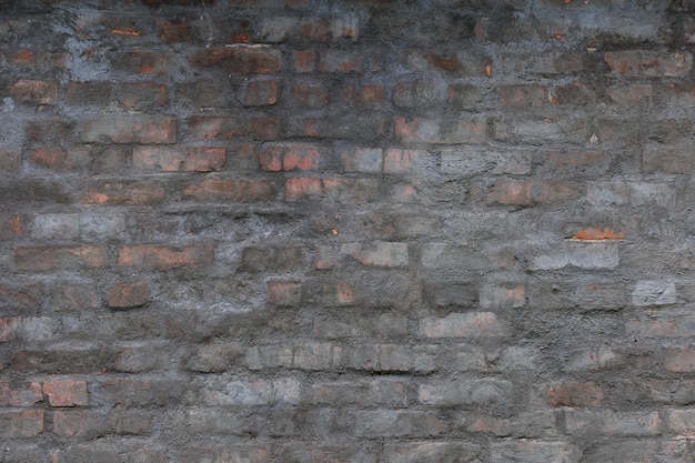 Viejo muro de ladrillo con capa de yeso de cemento gris en mal estado