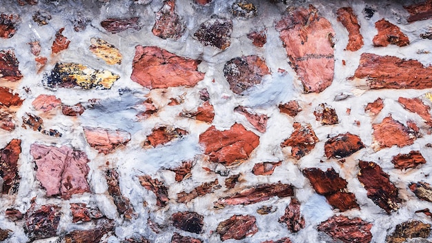 Viejo muro de piedra cercano en paleta beige suave con cemento Fondo de la superficie del muro de piedra con textura natural detallada fachada del edificio histórico