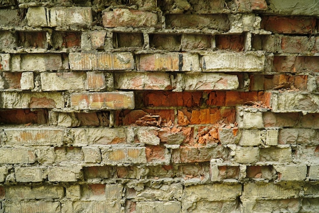 Un viejo muro que se desmorona con ladrillos destruidos entre un mas fuerte