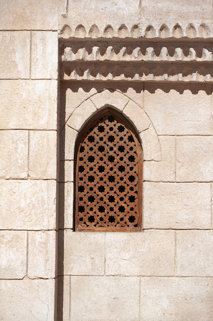 Viejo muro con una ventana con rejilla ornamental