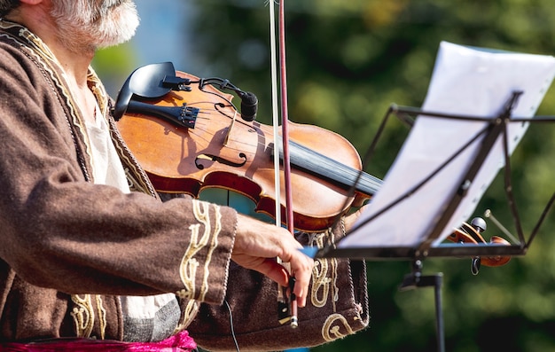 Viejo músico con un violín en la calle cerca de un mostrador de música con notes_