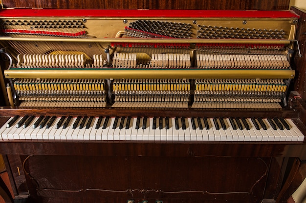 Viejo piano roto de pie en la pared