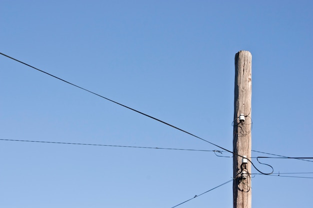 Viejo poste de madera decrépito del teléfono contra un cielo azul del gradiente