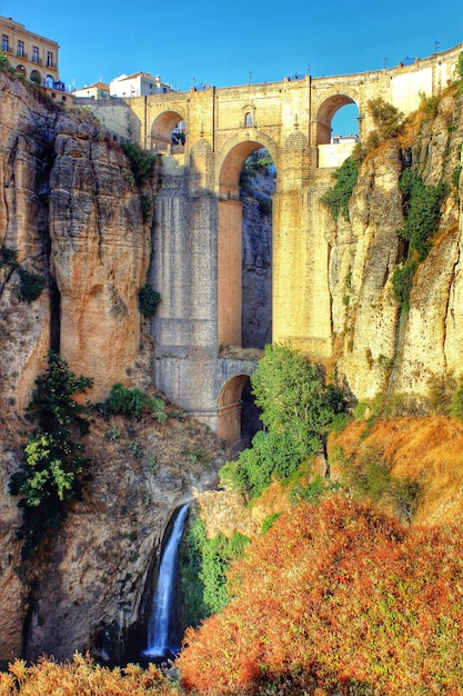 Foto viejo puente histórico sobre una cascada contra un cielo azul claro