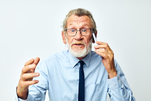 Viejo con teléfono en estudio sobre fondo blanco hablando