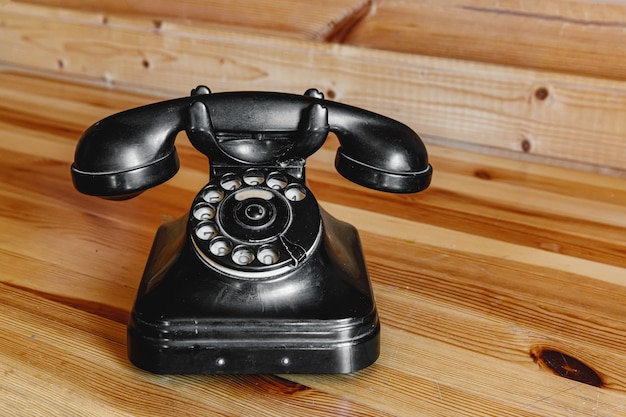 Viejo teléfono negro vintage en mesa de madera.