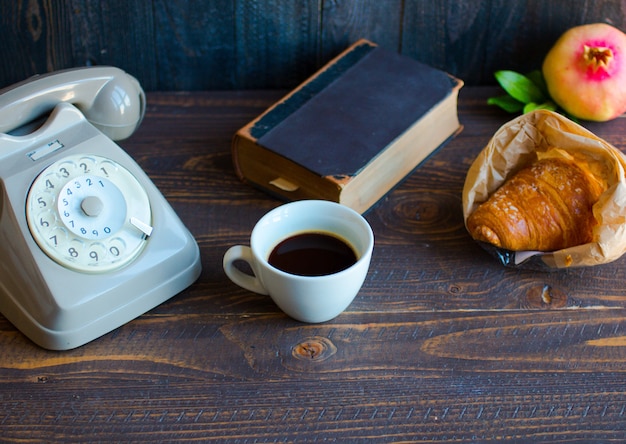 Viejo teléfono vintage, café, libro, sobre una superficie de madera