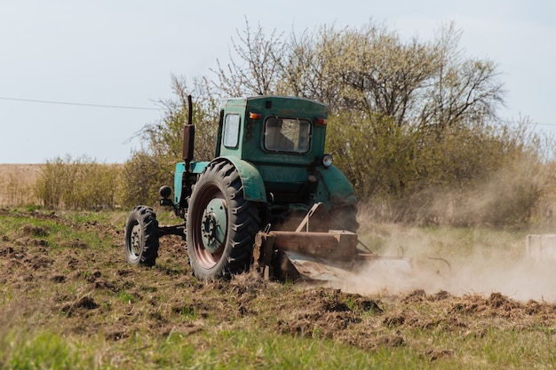 Un viejo tractor azul ara un campo y cultiva la agricultura del suelo