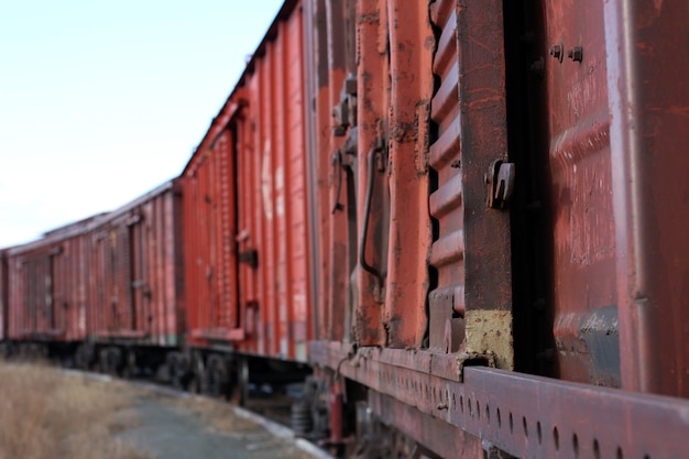 Viejo tren de mercancías oxidado se encuentra sobre rieles en primer plano en nitidez más borrosa desde el medio del vagón hasta el final del tren