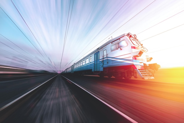 Viejo tren suburbano en movimiento contra el fondo del ferrocarril ucraniano de la puesta del sol del amanecer